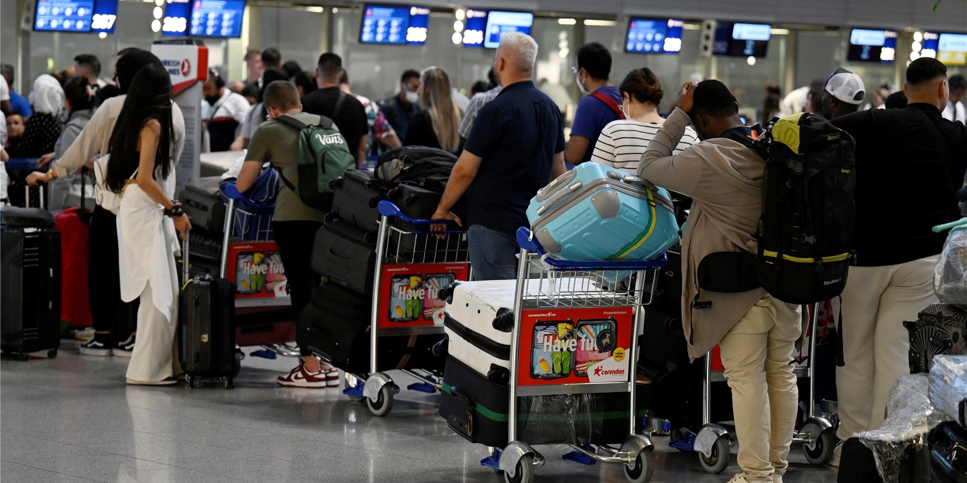 Reisende stehen in Schlangen vor den Check-In-Schaltern im Terminal am Düsseldorfer Flughafen.