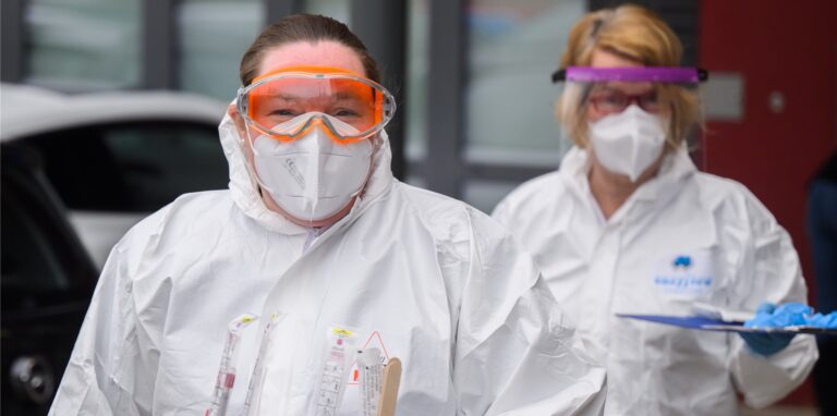 Eine Hausärztin (l.) und eine Arzthelferin stehen vor einer Arztpraxis, um Patienten mittels PCR-Test auf das Coronavirus zu testen. (Symbolfoto)