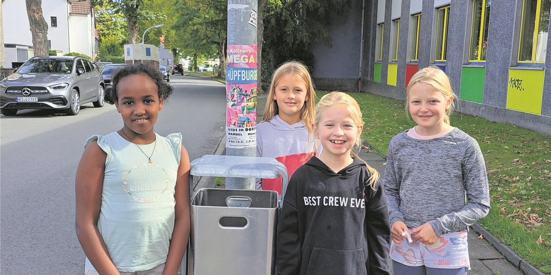 Vier Kinder stehen rund um einen neuen Abfallbehälter.