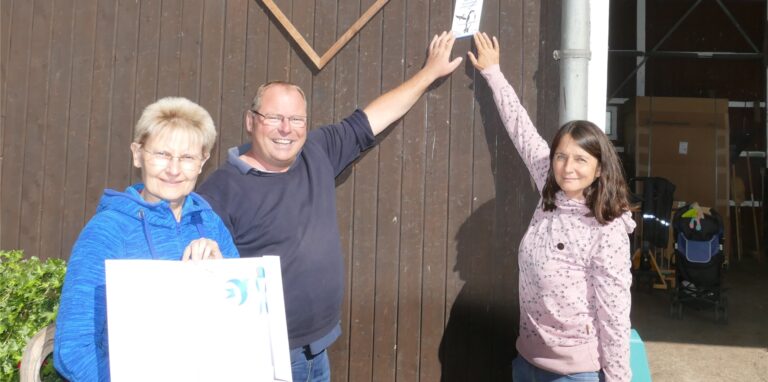 Bärbel Löhr mit Susanne und Karl-Heinz Trappe mit NABU-Plakette vor einem Scheunentor in Waltrop-Oberwiese.
