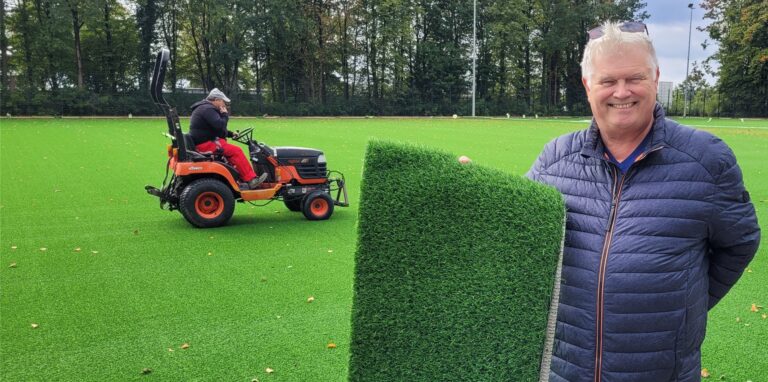 Stadt-Dezernent Michael Grzeskowiak präsentiert ein Stück Kunstrasen auf dem neuen Sportplatz am Steinrapener Weg in Oer-Erkenschwick.