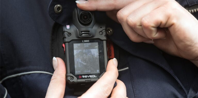 Eine Polizistin zeigt eine Body-Cam.