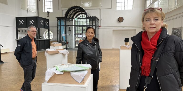 Doreen Becker (r.), Suria Kassimi und Manfred Guse stehen vor einigen Exponaten der Ausstellung „Kaleidoskop Heimat Querbeet“ in der Maschinenhalle Herten-Scherlebeck.