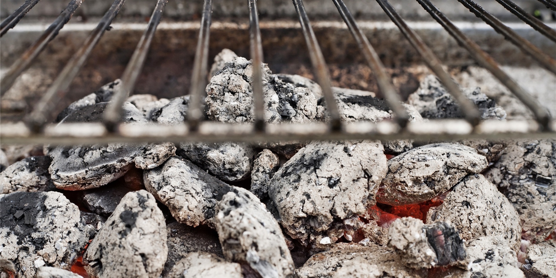 Grillbriketts glühen unter einem Grillrost.