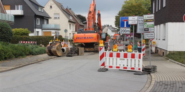Blick in die Straße Am Schwarzbach in Waltrop: Dort ist ein Baustellenzaun, mehrere Hinweis-Schilder und mehrere Baufahrzeuge zu sehen. Die Straße ist zurzeit gesperrt.