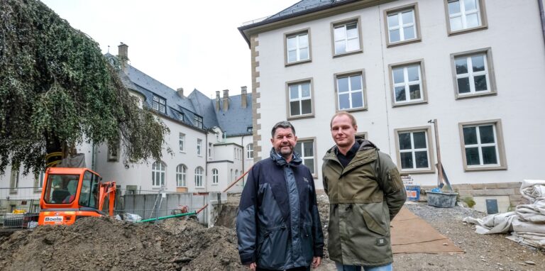 Zwei Männer stehen vor einem historischen Gebäude.