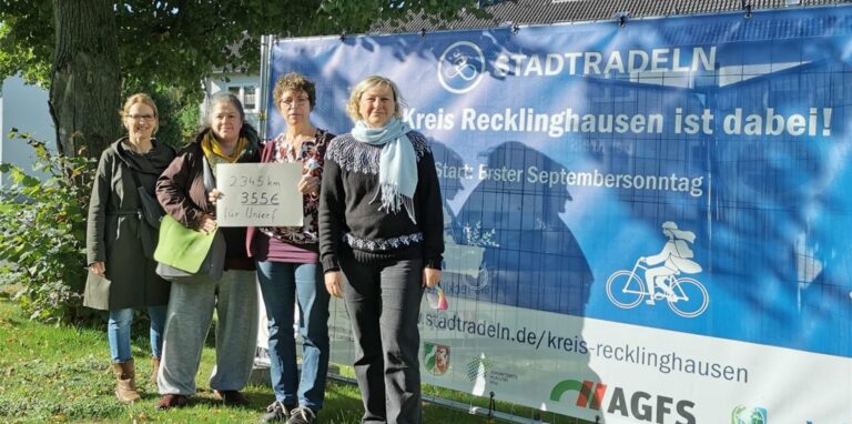 Britta Uebelhöde, Angelika Neuleben, Dagmar Uzoh und Dr. Astrid Hüdepohl von der evangelischen Kirchengemeinde Waltrop stehen mit einem Zettel, auf dem „2345 Kilometer – 355 Euro für Unicef“ steht, vor einem Stadtradeln-Plakat.