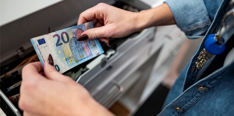 Eine Mitarbeiterin legt Geld in die Kasse in einem Bekleidungsladen in einem Einkaufscenter in Berlin-Marzahn.