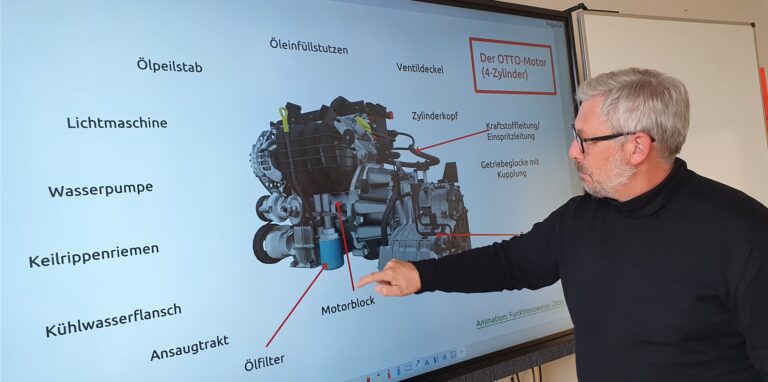 An der digitalen Tafel hat Rainer Pawliczek, Leiter der Willy-Brandt-Schule, einen Otto-Motor eingeblendet. Mit dem Finger zieht er rote Pfeile von den Begriffen am Rand auf die Bauteile.