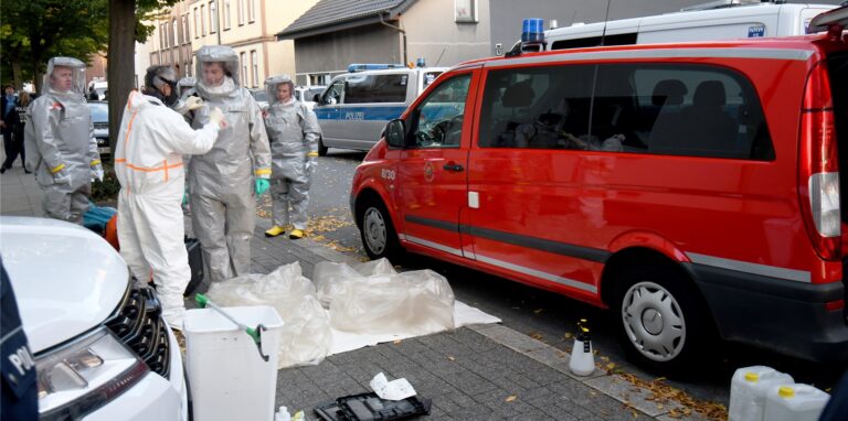 Großeinsatz von Polizei und Feuerwehr an der Augustastraße in Herten-Süd: In Schutzanzügen tragen die Einsatzkräfte mögliche Beweismittel aus einem Haus auf die Straße.