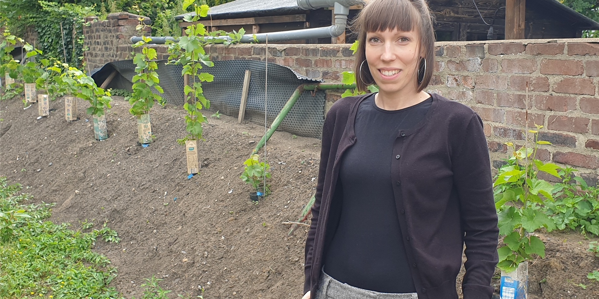 Sarah Höhle steht an einem Beet im Garten.