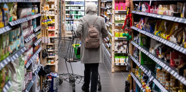 Kundin mit Einkaufswagen in einem Supermarkt.