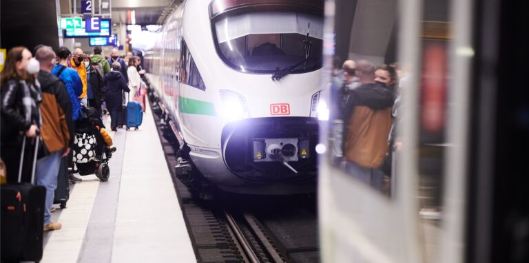 Viele Menschen stehen am Gleis im Hauptbahnhof Berlin, als ein ICE einfährt.