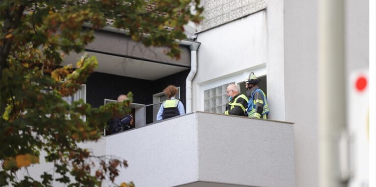 Ermittler und Feuerwehrleute stehen auf dem Balkon eines Mehrfamilienhauses in Gevelsberg.
