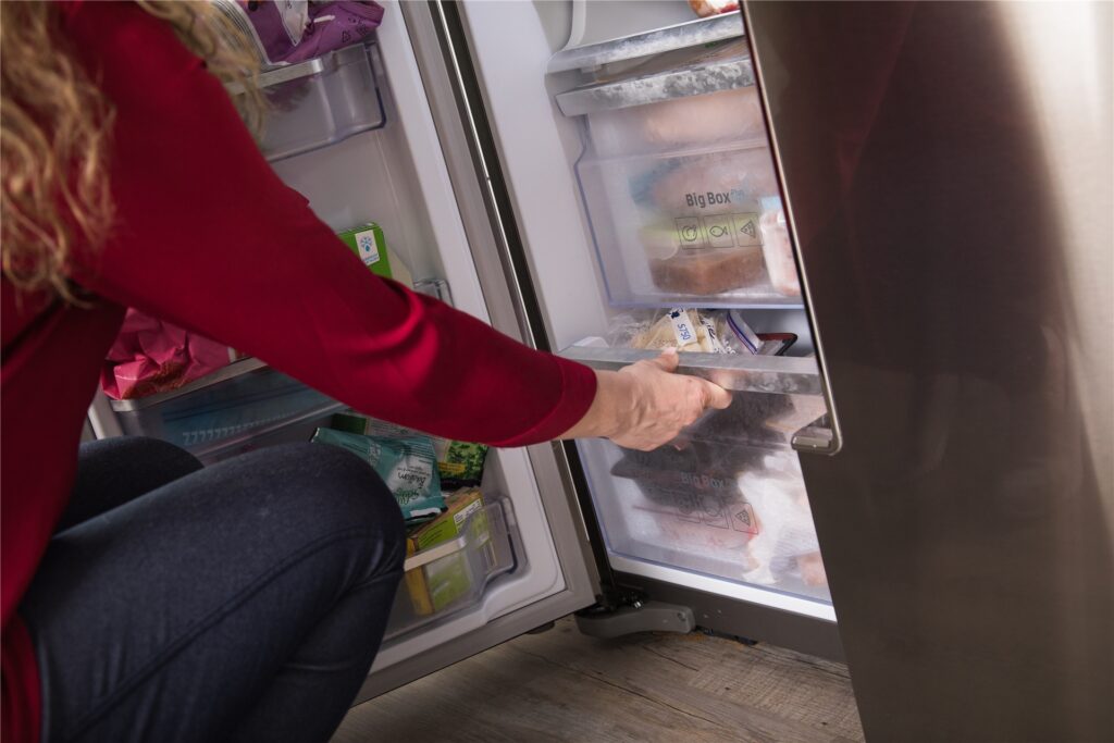 Eine Frau guckt in den Gefrierschrank