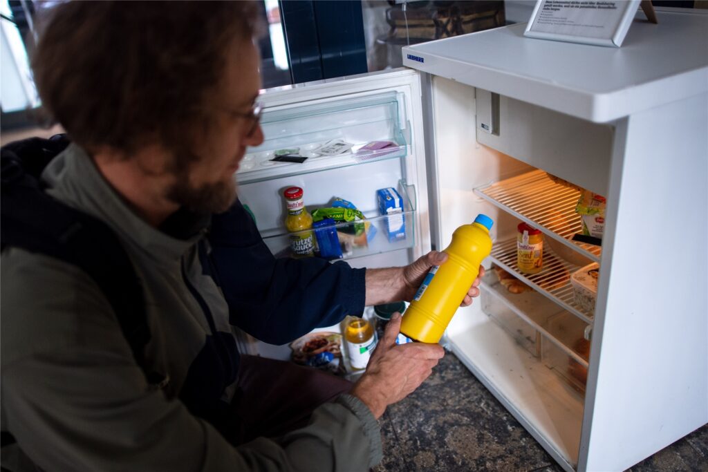 Ein Mann packt Lebensmittel in einen Kühlschrank der 