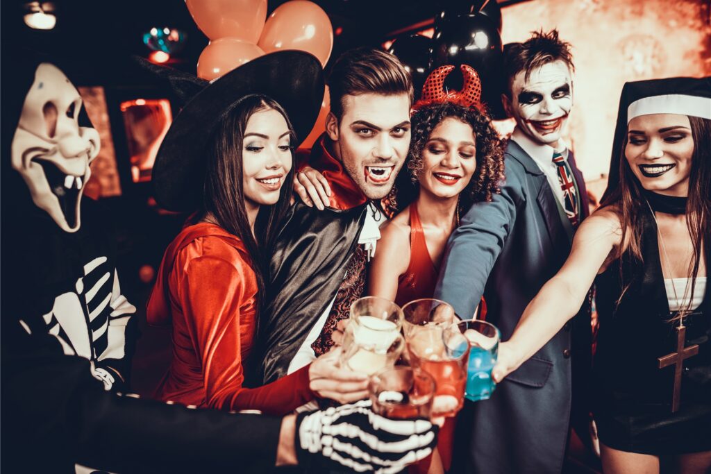 verkleidete menschen stoßen auf einer halloween party mit drinks an