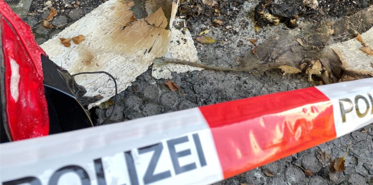 Flatterband der Polizei und ein geschmolzenes Rücklicht einer schwarzen Limousine. Im Hintergrund die Überreste des Brandanschlags an der Habinghorster Straße.
