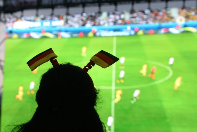 Ein Fußballfan schaut ein Spiel auf einer Großleinwand