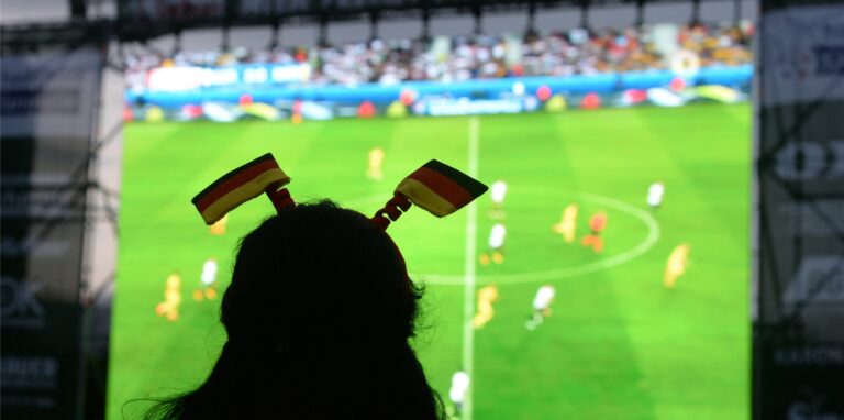 Ein Fußballfan schaut ein Spiel auf einer Großleinwand