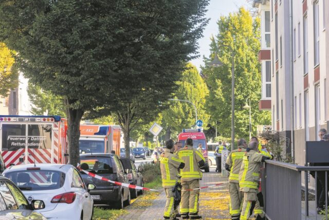 Feuerwehrleute stehen in Waltrop vor einem Mehrfamilienhaus.