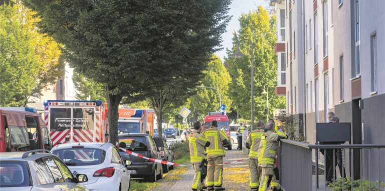 Feuerwehrleute stehen in Waltrop vor einem Mehrfamilienhaus.