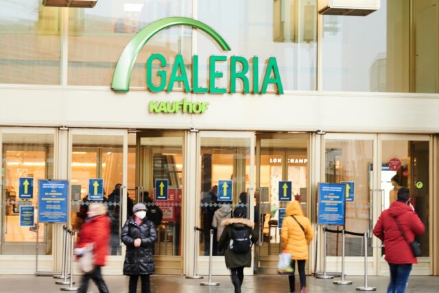 Menschen kommen aus oder gehen in den Galeria Kaufhof am Alexanderplatz.
