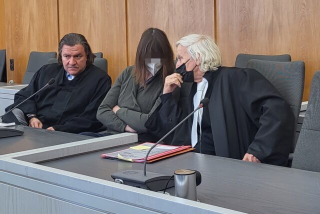 Eine Angeklagte und zwei Anwälte im Gerichtssaal