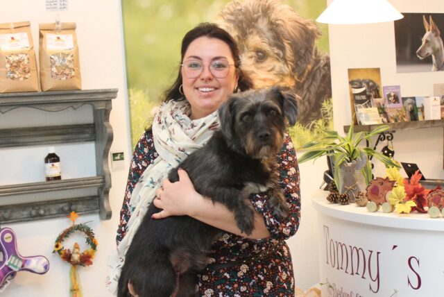 Jana Große hat ihren Hund Baloo auf dem Arm und steht in ihrem Laden, Tommys Barfshop in Waltrop.