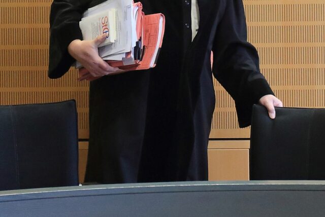 Ein Richter rückt sich in einem Verhandlungssaal seinen Stuhl zurecht.