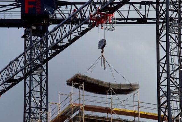 An einem Baukran wird Baumaterial auf einer Baustelle des Quartiers Heidestraße in Berlin transportiert.