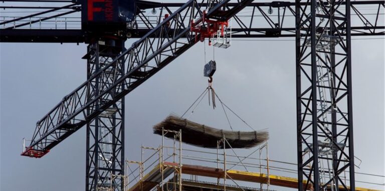 An einem Baukran wird Baumaterial auf einer Baustelle des Quartiers Heidestraße in Berlin transportiert.