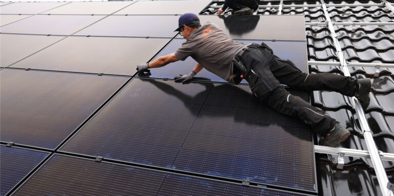 Handwerker montieren auf dem Dach eines Wohnhauses Solarmodule.