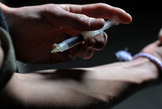 Symbolbild: Eine Person hält sich eine Drogen-Spritze an den Arm.