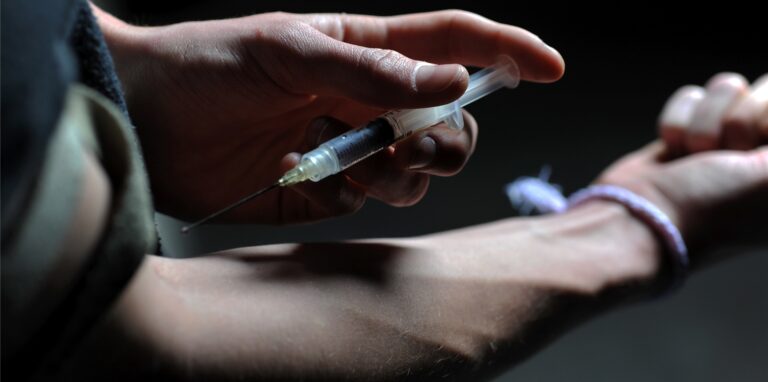 Symbolbild: Eine Person hält sich eine Drogen-Spritze an den Arm.