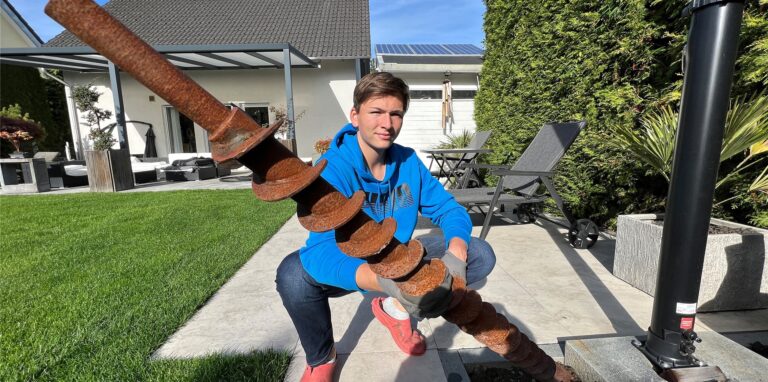 Jonas Kalla steht mit einem Bohrgestänge in seinem Garten.