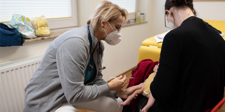Eine Kinderärztin impft in einem Behandlungszimmer ihrer Kinderpraxis einen Säugling