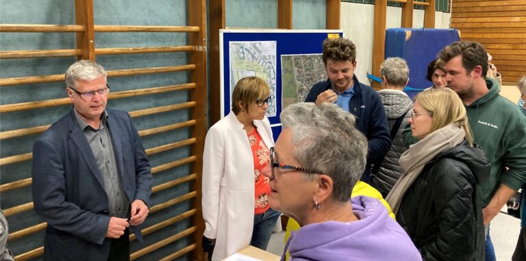 Stadtplanungsamtsleiter Markus Schaffrath (l.) und Baudezernentin Andrea Baudek (M.) diskutieren mit den anwesenden Bürgerinnen und Bürgern über die verschiedenen Varianten des Rewe-Feldmann-Umzugs.