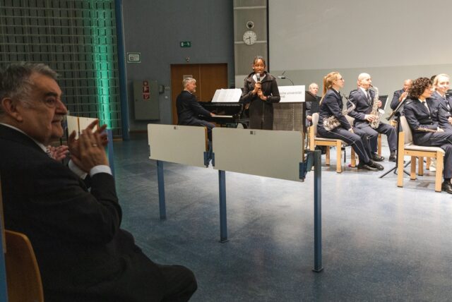 Herbert Reul sitzt applaudierend vor den Musikern.