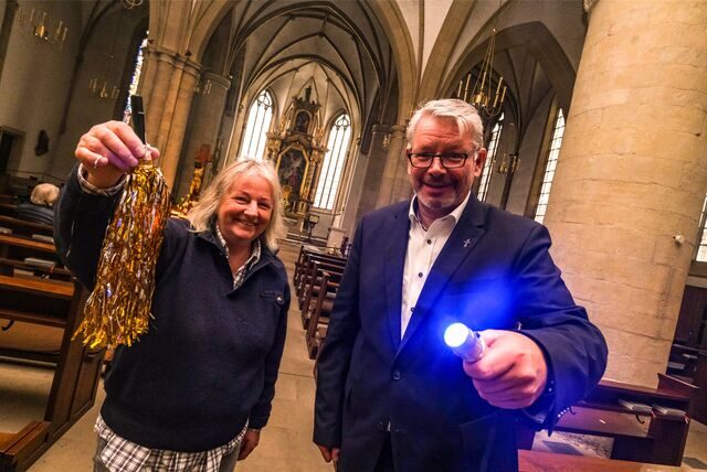 Eine Frau und ein Mann stehen in einer Kirche und halten Taschenlampen in der Hand.