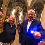 Eine Frau und ein Mann stehen in einer Kirche und halten Taschenlampen in der Hand.