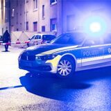 Ein Streifenwagen der Polizei steht vor einer Häuserreihe.