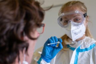 Eine Frau in Schutzkleidung führt einen Corona-Test durch.
