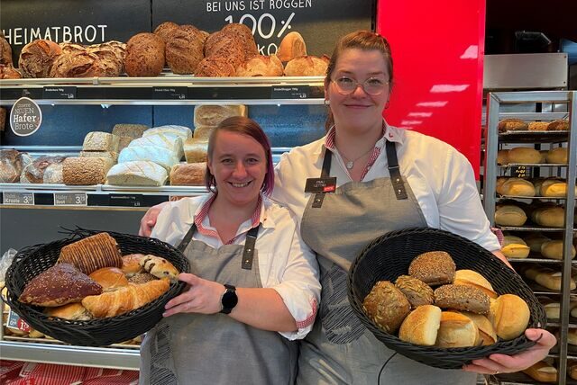 Zwei Frauen stehen mit einem Korb Brötchen in der Hand vor der Bäckereiauslage bei Geiping am Dümmerweg.
