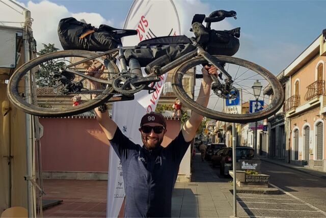 Kilian Wagner, Mitarbeiter von Hase Bikes in Waltrop, hält sein Fahrrad im Ziel des „Two Volcano Sprints“ in die Höhe.