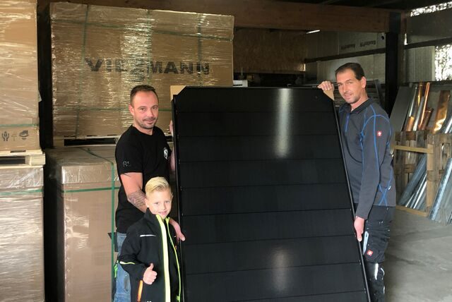 Enrico Jacobs (l.) mit Sohn Lionel und Dachdeckermeister Sven Kottkamp zeigen ein Modul einer Photovoltaik-Anlage.