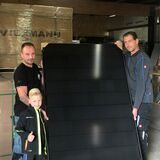 Enrico Jacobs (l.) mit Sohn Lionel und Dachdeckermeister Sven Kottkamp zeigen ein Modul einer Photovoltaik-Anlage.