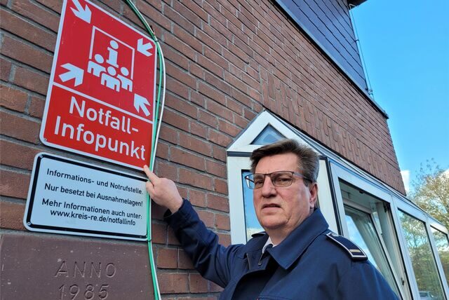 Feuerwehrchef Gerd Pokorny zeigt auf das Schild, das den Notfall-Infopunkt an der Feuer- und Rettungswache kennzeichnet.