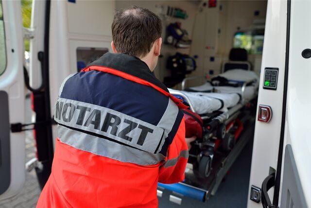 Ein Notarzt zieht eine Krankenliege aus einem Rettungswagen.