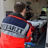 Ein Notarzt zieht eine Krankenliege aus einem Rettungswagen.
